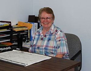 Sr. Linda smiling behind desk